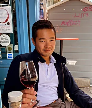Photo of me smiling in a white shirt holding a glass of red wine